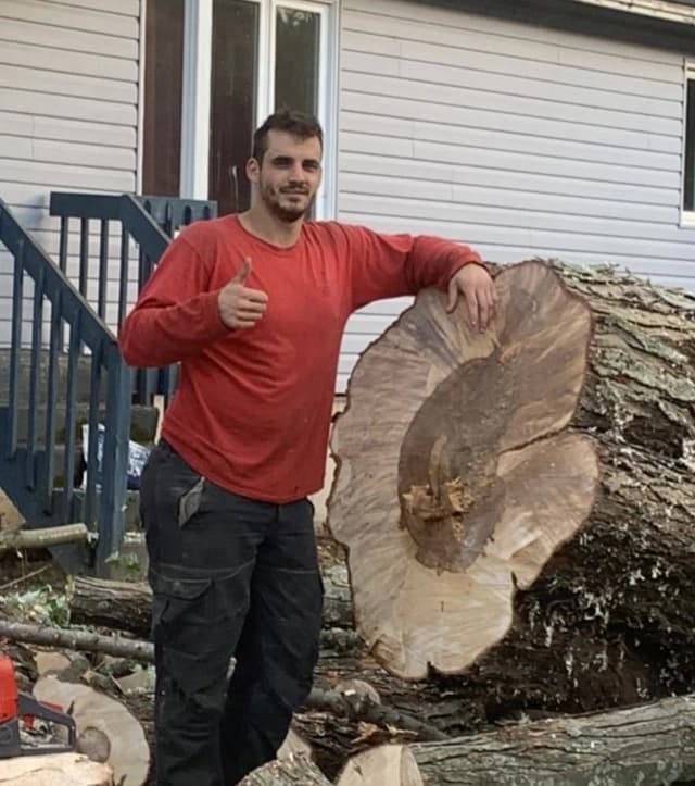 Sébastien Gaudet devant une bille de bois après abattage