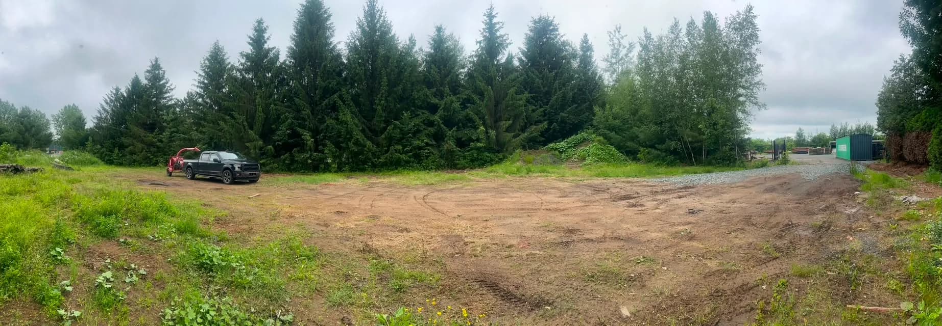 Grand terrain résidentiel fraîchement déboisé à Saint-Samuel, camion Apex et déchiqueteuse en bordure, lisière d'épinettes conservée à l'arrière